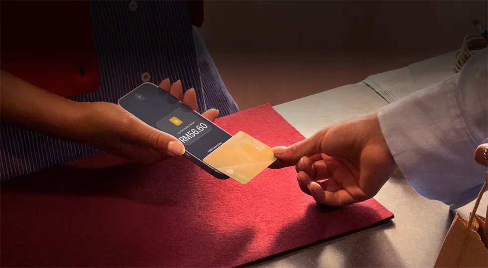 A hand taps a credit card to an iPhone to complete a payment