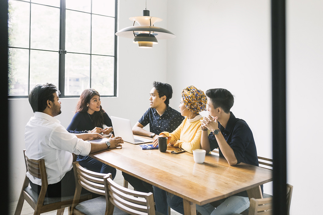 981058294 Group of young startupers having a meeting in a loft style meeting room