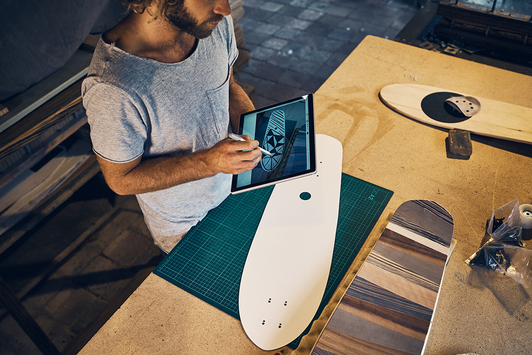 Shot of a young man designing a skateboard on his tablet in the workshop